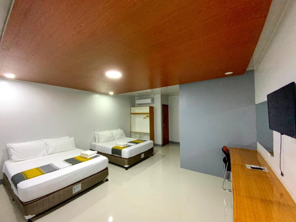 a bedroom with two beds and a wooden ceiling at ICON Venue and Suites in General Santos