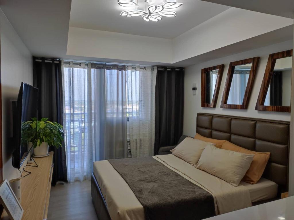 ein Schlafzimmer mit einem großen Bett und einem TV in der Unterkunft Skycourt Suites at Azure North Pampanga Condominium in San Fernando