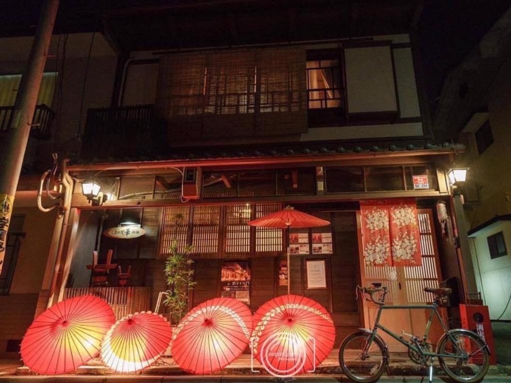 a group of red umbrellas in front of a building at Guesthouse HANA Nishijin in Kyoto
