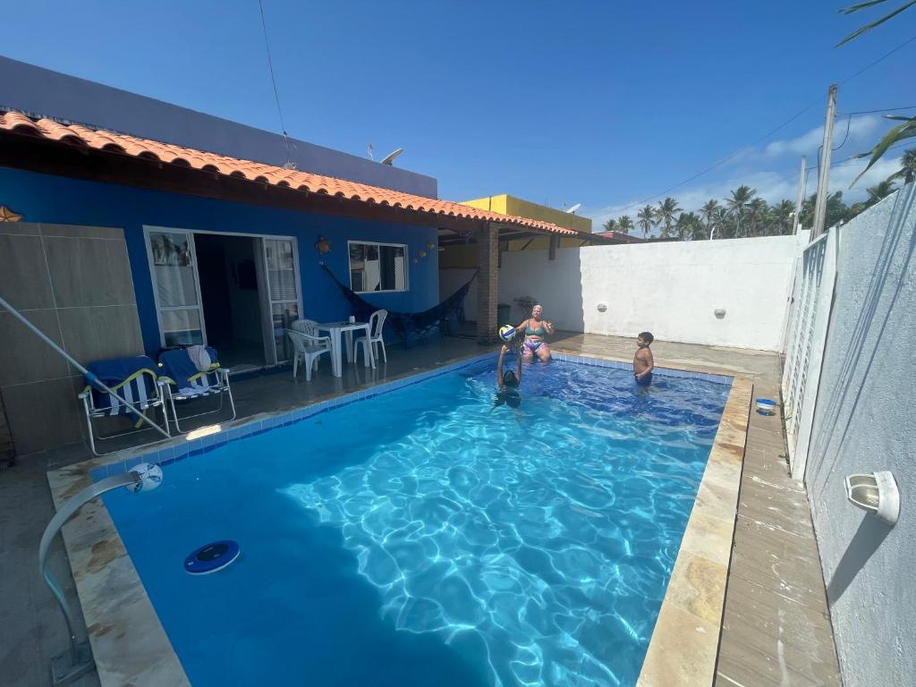 um homem e duas crianças brincando em uma piscina em Casa de Praia Aconchego São José da Coroa Grande em São José da Coroa Grande