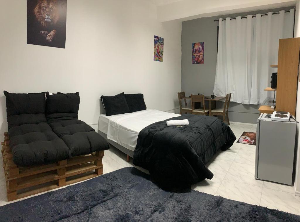 a bedroom with a bed and a couch and a table at Studio 308 - Apartamento Passo Fundo in Passo Fundo