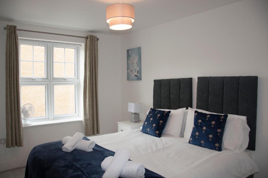 Watford Gemini Hurst في واتفورد: غرفة نوم بسرير ذو شراشف بيضاء ومخدات زرقاء