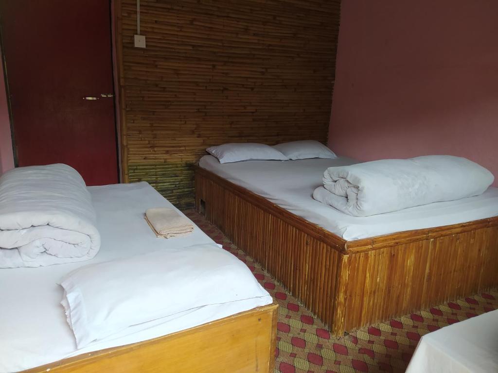 2 camas en una habitación con sábanas y almohadas blancas en Hotel new bamboo palace, en Gorkhā