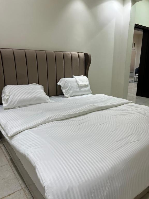 uma grande cama branca com duas almofadas em شقق مفروشة em Riyadh