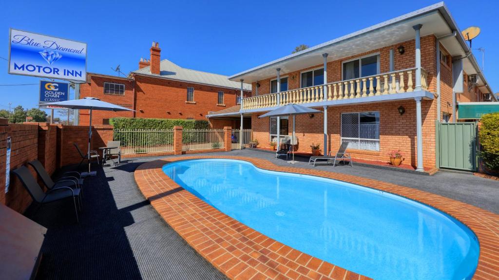 a swimming pool in front of a house at Blue Diamond Motor Inn in Dubbo
