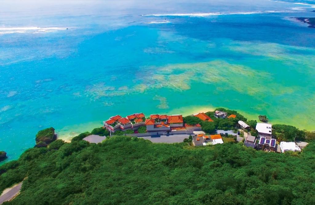 een groep huizen op een heuvel naast de oceaan bij Hyakunagaran in Nanjo