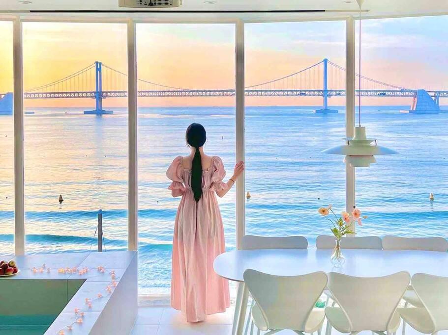 Una mujer con un vestido rosa mirando hacia el océano en Stay moment en Busan