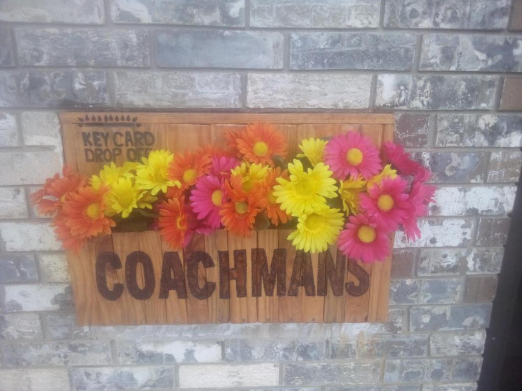un cartel en una pared de ladrillo con flores. en Coachman's Inn & Suites en Waldron