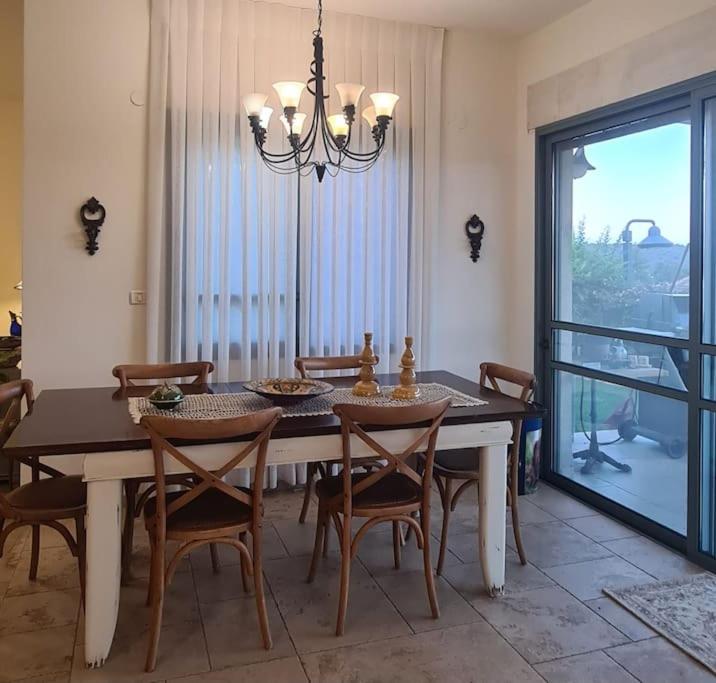uma mesa de jantar com cadeiras e um lustre em בית לוי em Dishon