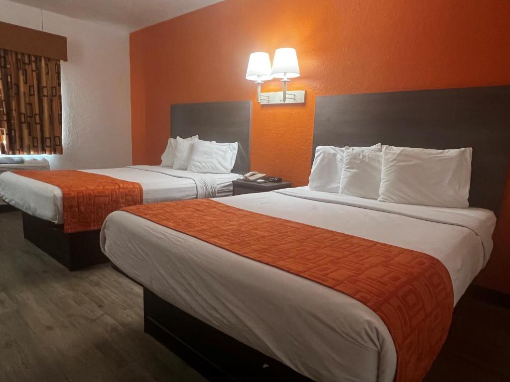 una camera d'albergo con due letti e pareti arancioni di Howard Johnson by Wyndham Galveston a Galveston