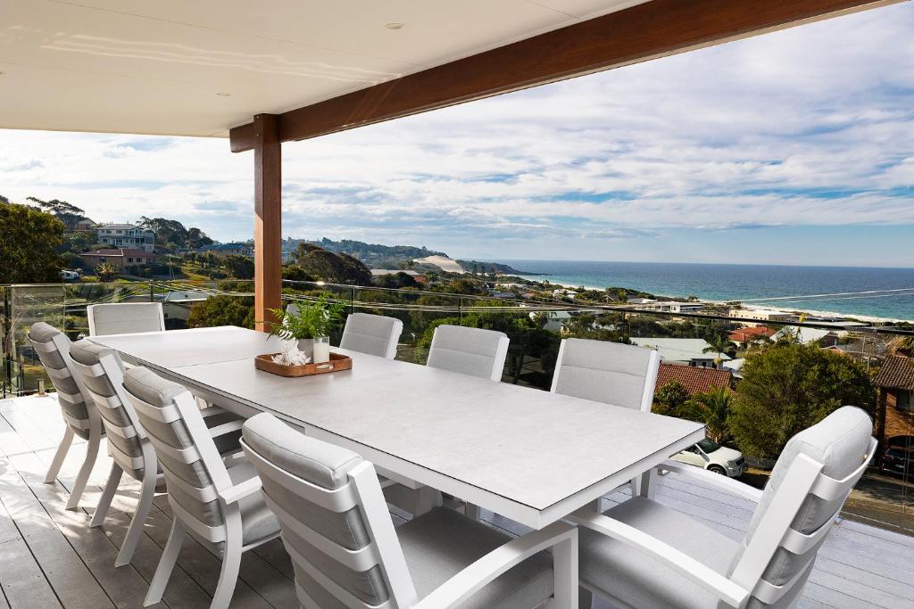 - une table et des chaises blanches sur un balcon donnant sur l'océan dans l'établissement Palm Breeze, à Forster