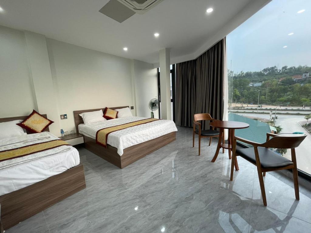 Habitación de hotel con 2 camas, mesa y sillas en Snu Motel - Cao Bằng, en Cao Bằng