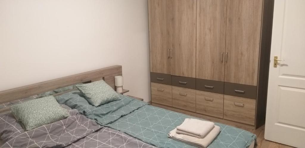 een slaapkamer met een bed en een houten kast bij Jószerencsét apartman in Komló