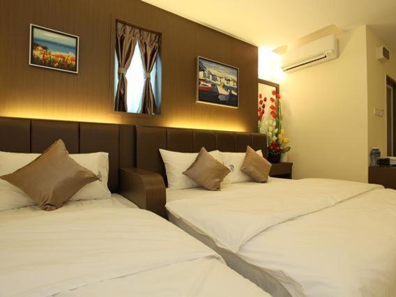 2 letti posti uno accanto all'altro in una camera da letto di Avaria Signature Hotel a Malacca