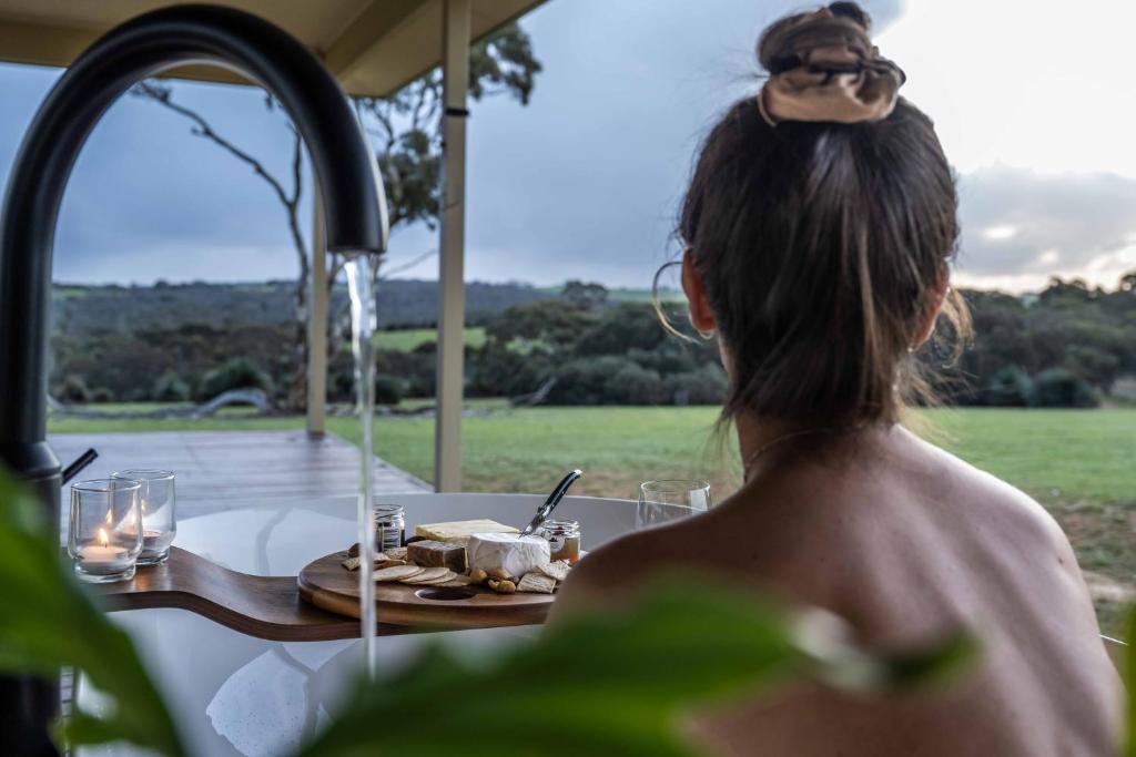 una mujer sentada en una mesa con un plato de comida en Ecopia Retreat en Seal Bay