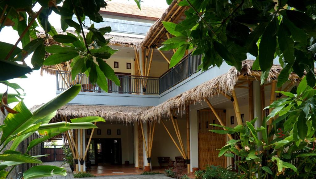 a building with thatched roofs and a courtyard at Vamana Bangsal in Pawenang