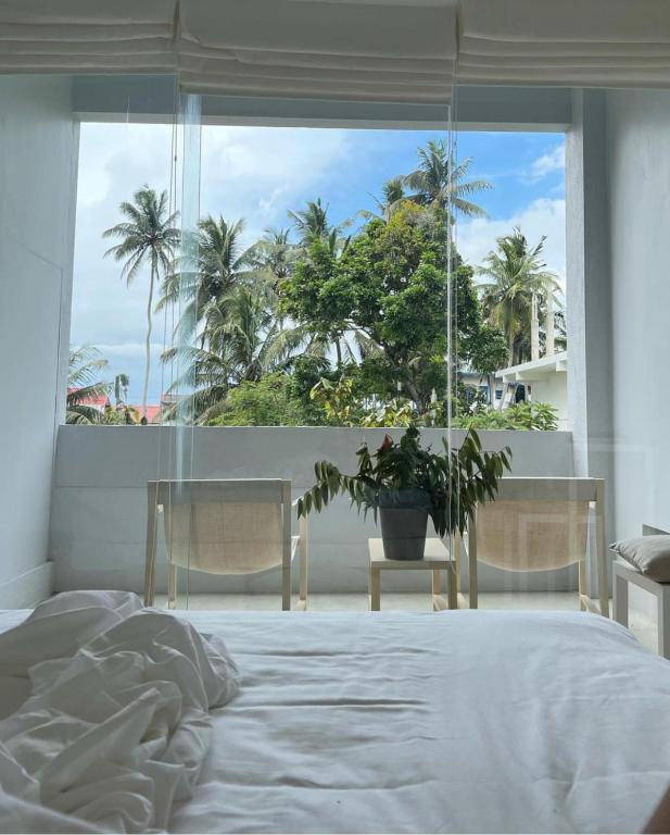 a bedroom with a bed and a window with palm trees at Saffron Robes Living in Hikkaduwa