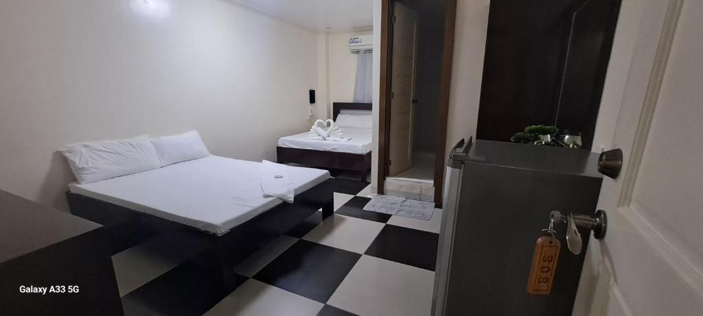Cette chambre comprend 2 lits et un sol en damier noir et blanc. dans l'établissement Bayside Exceel Hotel, à Puerto Galera