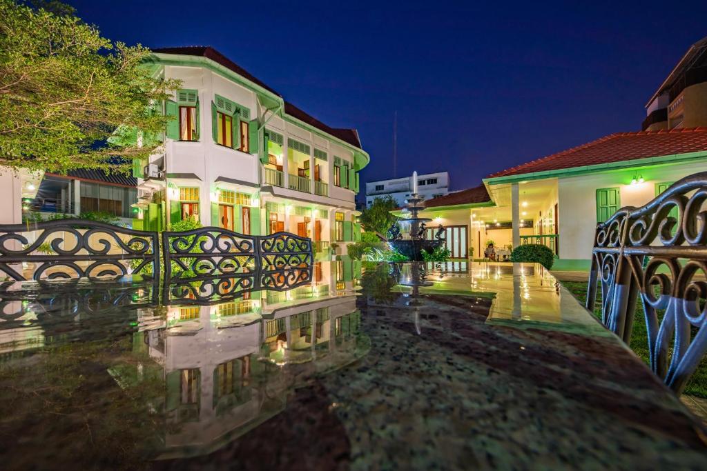 un edificio con una valla delante de él por la noche en วิลล่าขุนวิเชียรพานิช, en Phetchaburi