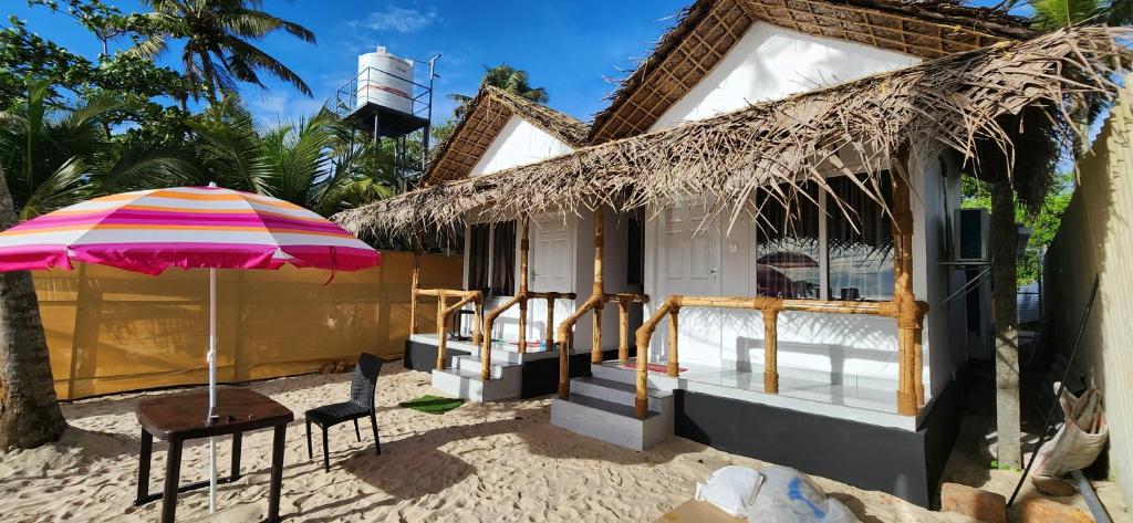 a house with a table and an umbrella on the beach at Bliss Beach Villa in Alleppey