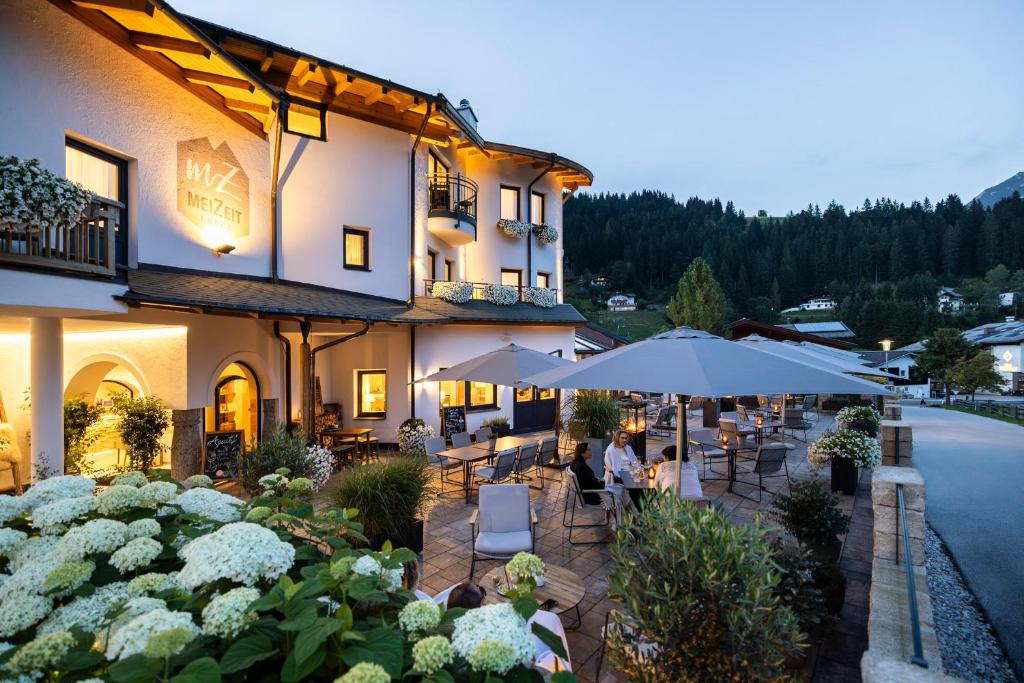 a restaurant with tables and umbrellas in front of a building at meiZeit Lodge in Filzmoos