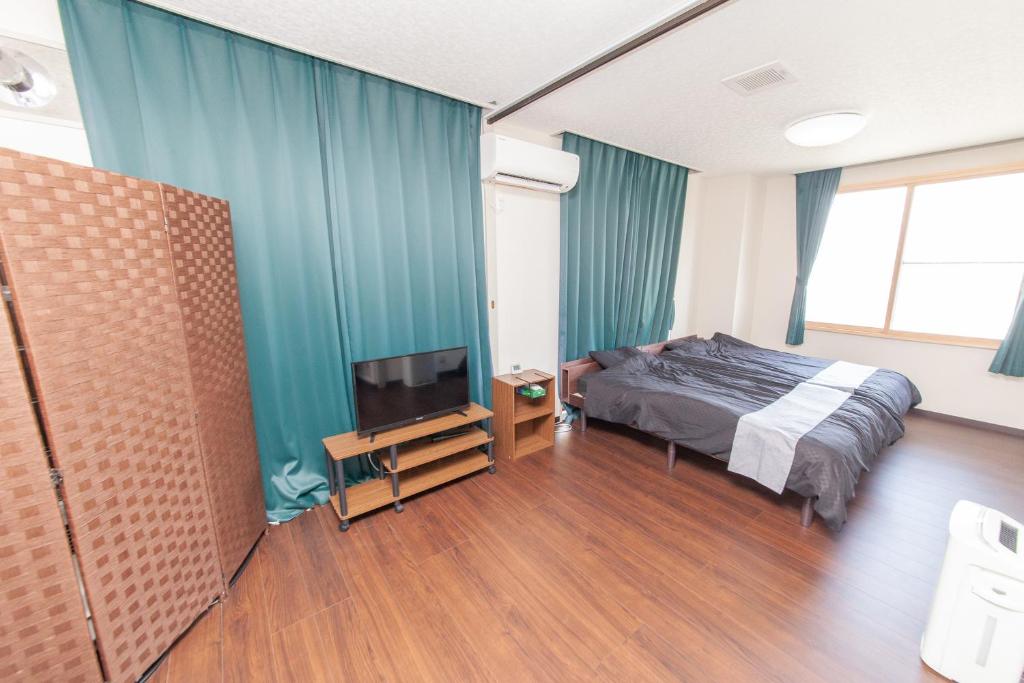 a bedroom with a bed and a flat screen tv at Big Stone Tsukuda 45平米 2SDbed 2For3F in Aomori