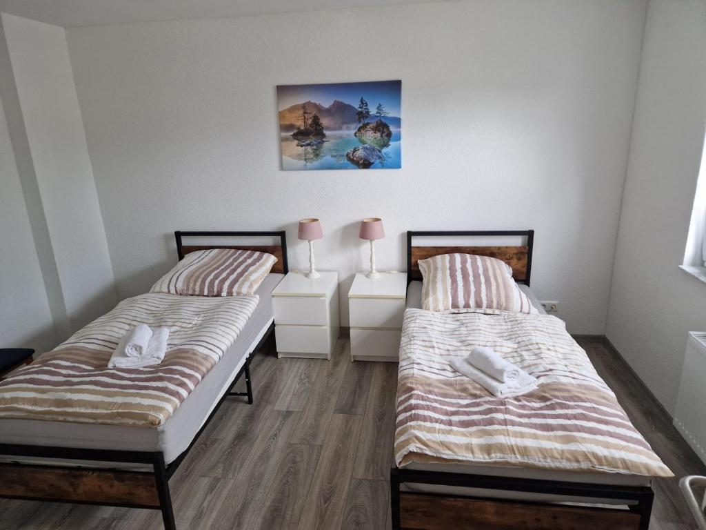 two beds in a room with wooden floors at Capital Apartments in Düren - Eifel