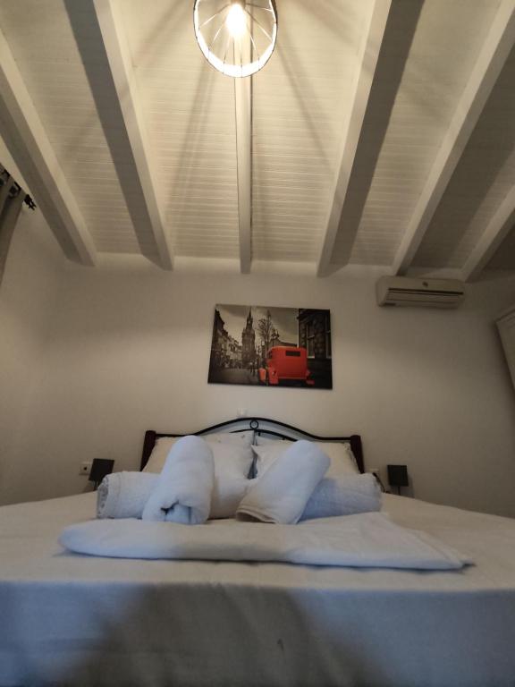 een slaapkamer met een bed met witte lakens en een licht bij Avra in Paralía Avlídhos