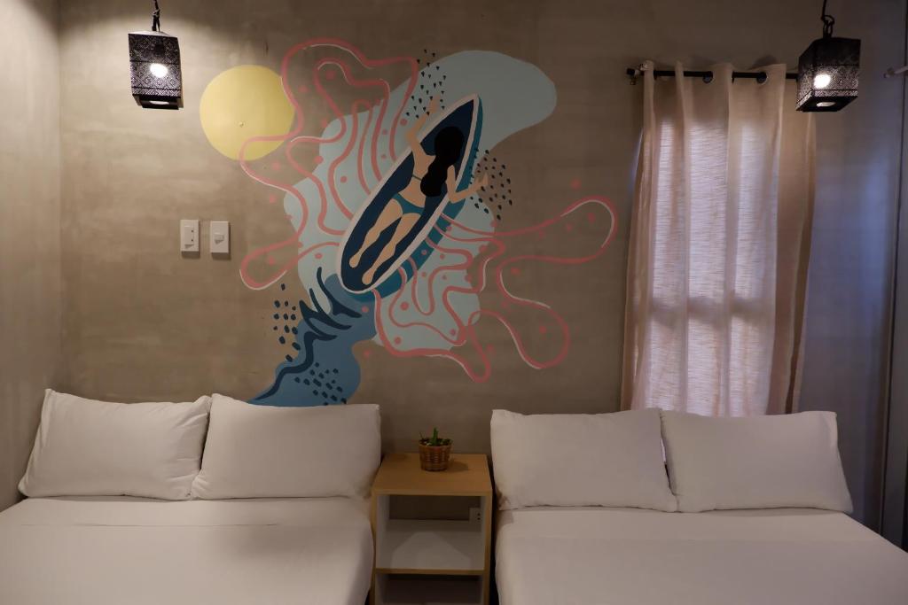 2 Betten in einem Zimmer mit Wandgemälde in der Unterkunft Lubihan Siargao in General Luna