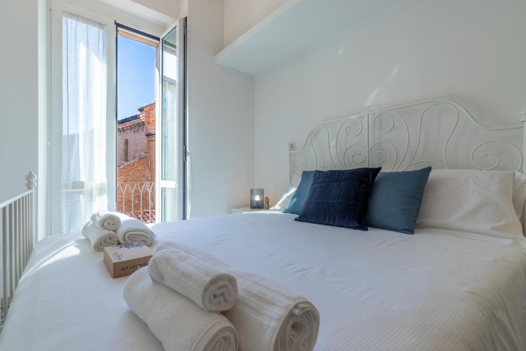 1 dormitorio con 1 cama blanca grande y toallas. en Italian Experience-Suite Santa Maria Gualtieri, en Pavia