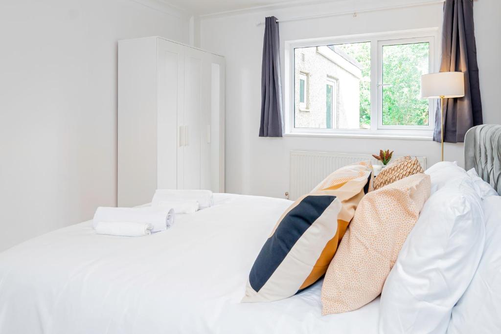 a white bedroom with a bed with pillows on it at Charming 2-Bedrooms Apartment with a Garden at Abingdon in Oxford