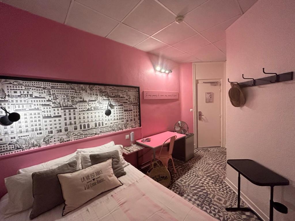 a bedroom with a pink wall with a bed and a desk at Hôtel de la Croix-Rousse in Lyon