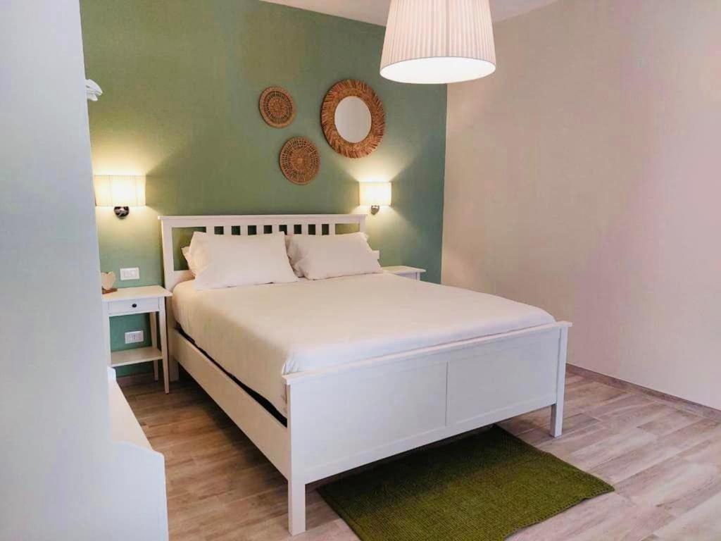 een slaapkamer met een wit bed en een groene muur bij Villa Blue Paradise - B&B con piscina non lontano da Cagliari in Cagliari