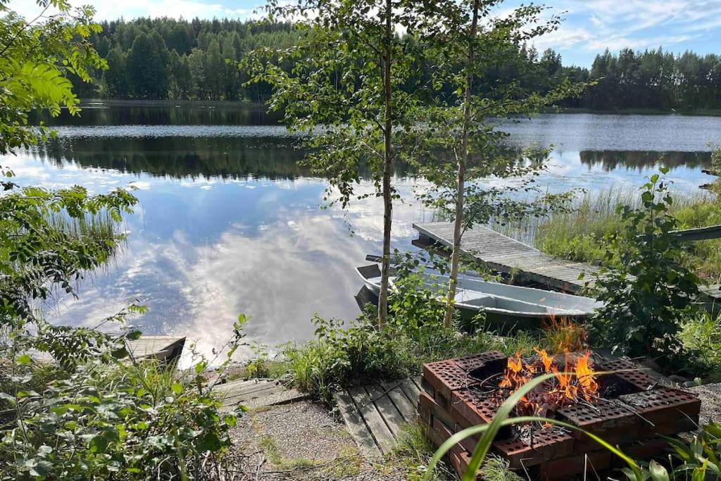 eine Feuerstelle neben einem See mit einem Dock in der Unterkunft Two bedroom cottage with peaceful views in Jyväskylä