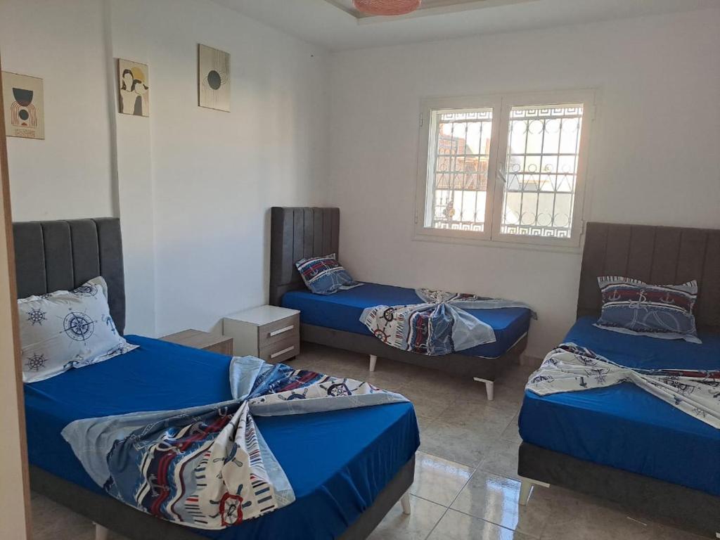 a room with three beds and a window at dari darkom in Kerkouene