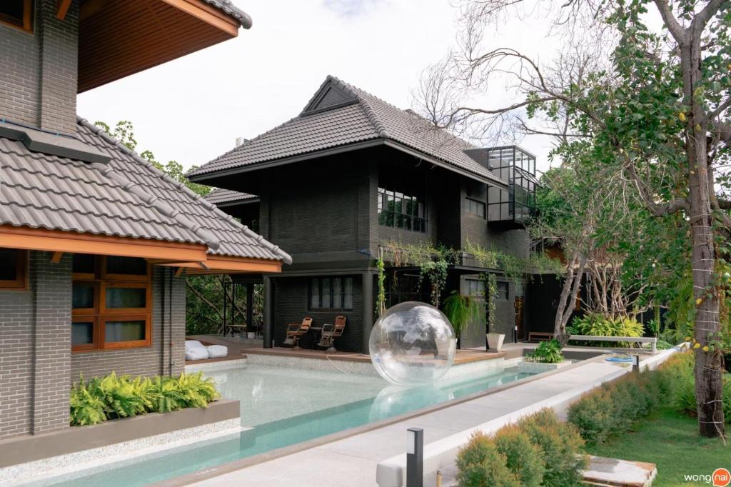 a house with a swimming pool in front of a house at Phrip Phri Luxury Pool Villas in Phetchaburi