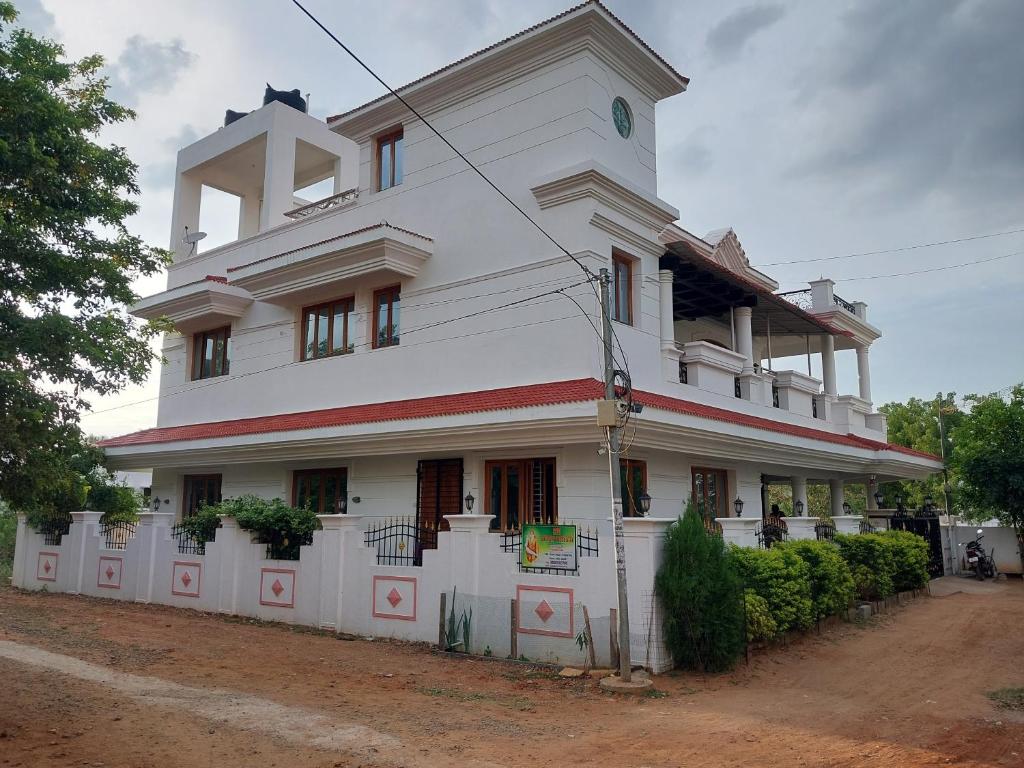 um grande edifício branco com uma cerca em frente em Shri Sai Baba Homestay - EB Colony - Trichy em Tiruchchirappalli
