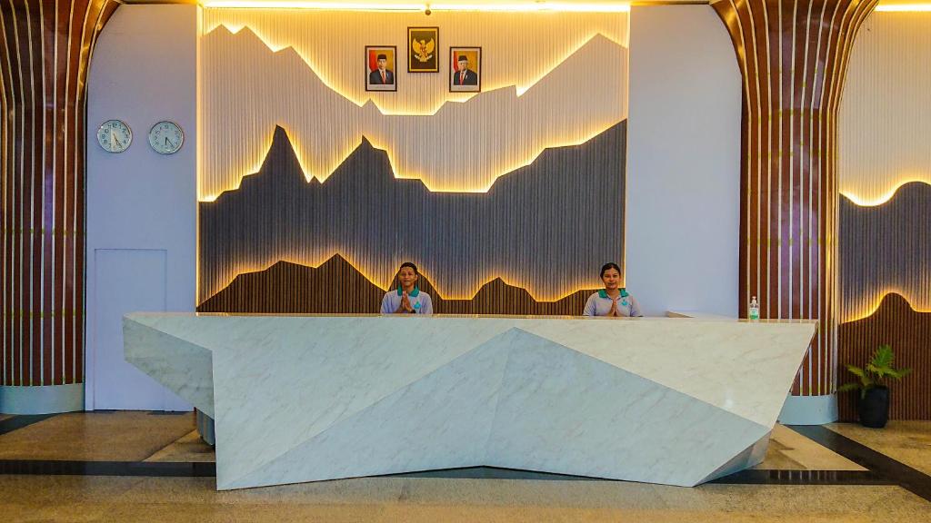Dos mujeres sentadas en una recepción en un vestíbulo en Agro Hotel Bintan en Teluk Bakau