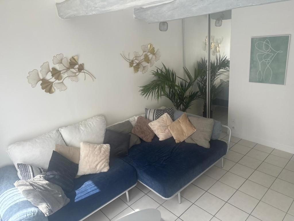 a living room with a blue couch with pillows at F2 cocooning centre ville 4 personne in Beaumont-sur-Oise