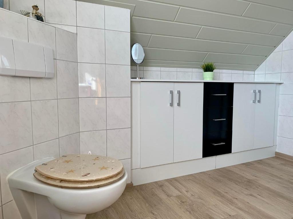 a white bathroom with a toilet with a wooden seat at Harms, Ferienwohnung in Südbrookmerland