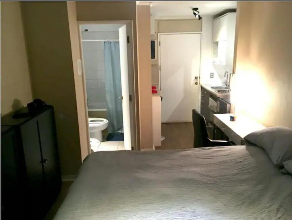 1 dormitorio con 1 cama y baño con lavamanos en Suit cerca aeropuerto y centro de la ciudad, en Santiago