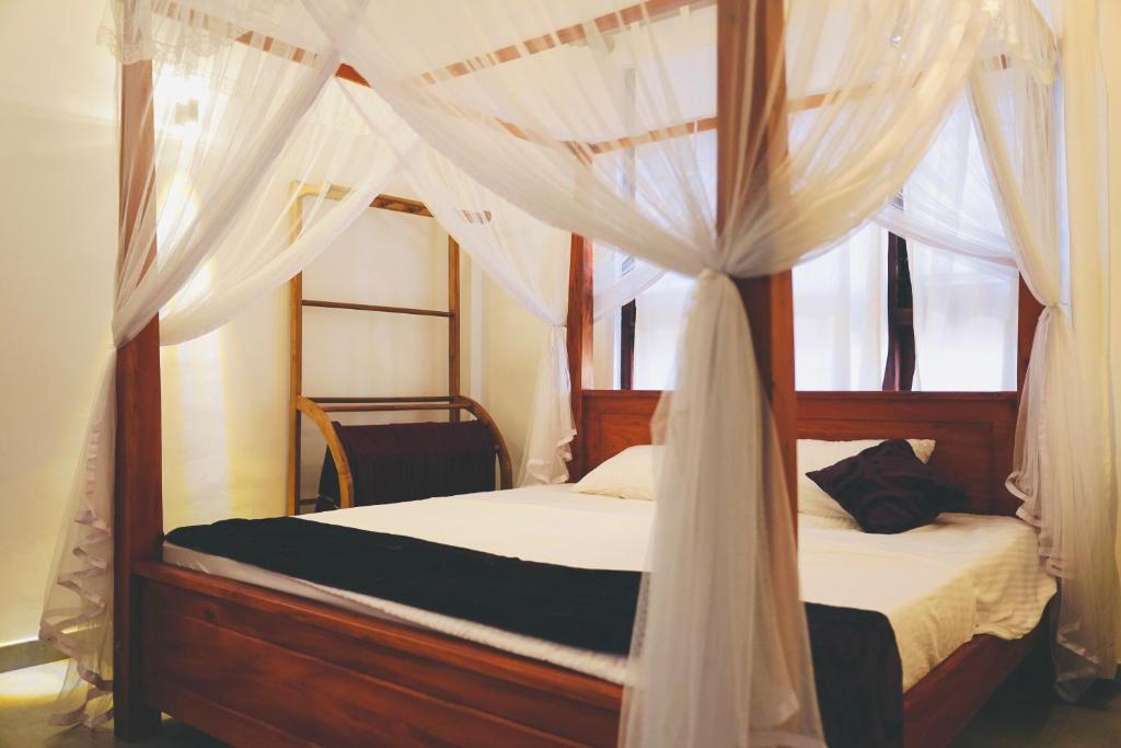 a bedroom with a canopy bed with white drapes at Soul Inn in Ahangama