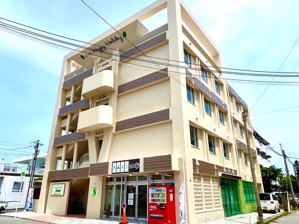 un edificio alto con una puerta roja delante de él en Hotel Happy Holiday Ishigaki en Isla Ishigaki