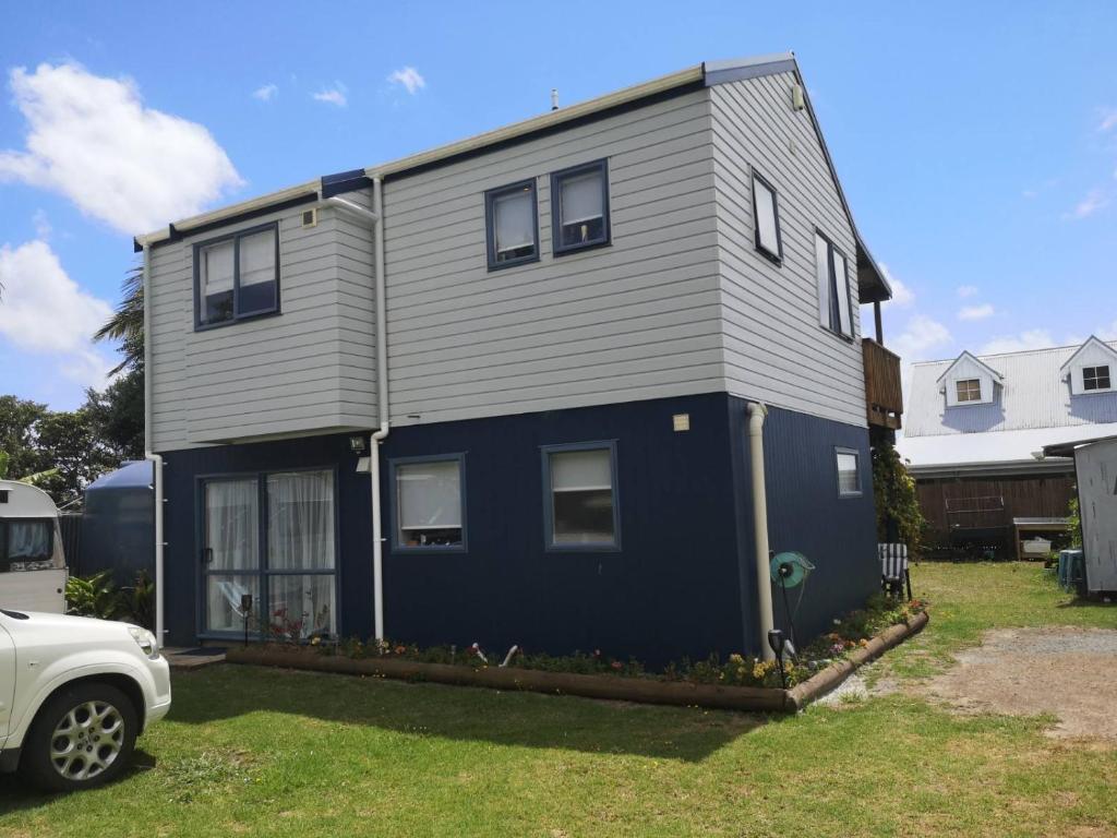 a blue and grey house with a car parked in front of it at Houhora Harbour Haven in Pukenui