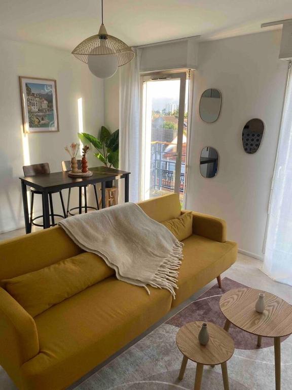 uma sala de estar com um sofá amarelo e uma mesa em Le Petit Paradis Parisien em Montmagny