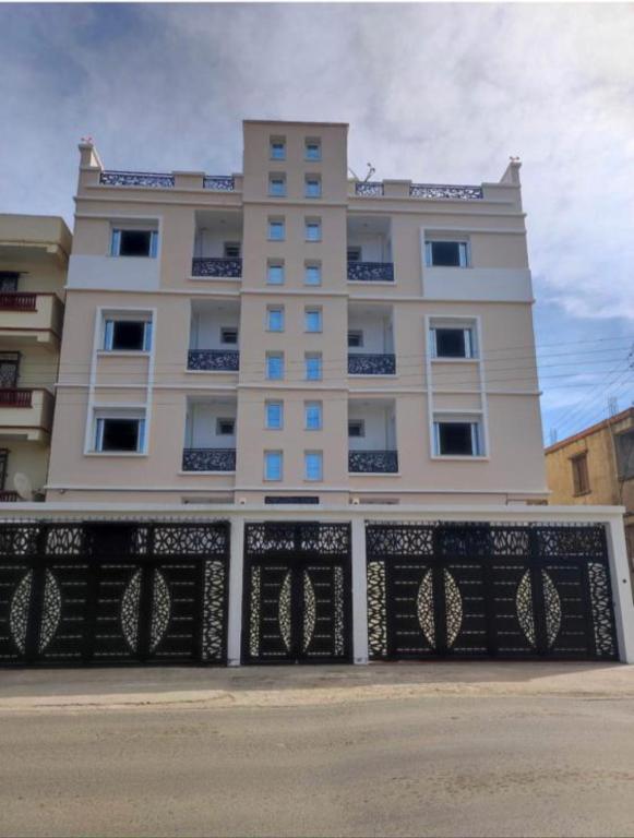 a tall white building with a fence in front of it at Résidence Le Figuier Marako, Tizi-Gheniff in Tizi Gheniff