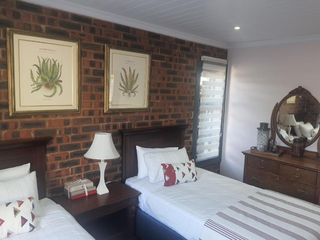 a bedroom with two beds and a brick wall at Spindrift Seaside Accommodation in Wilderness