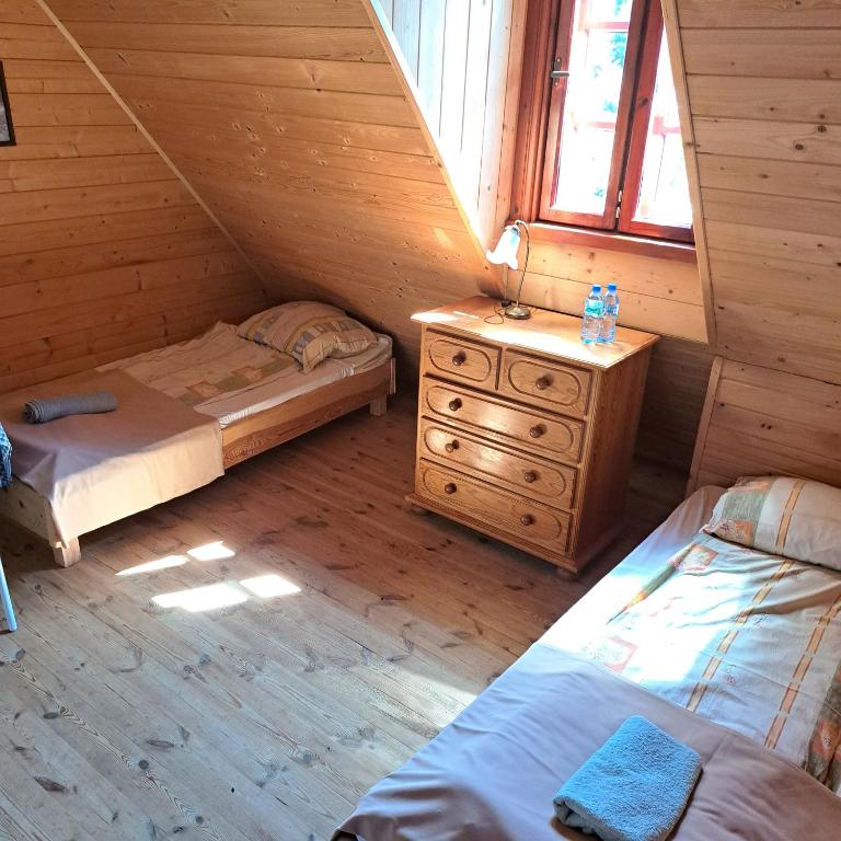 a bedroom with two beds and a dresser in a log cabin at Dom Glówny 