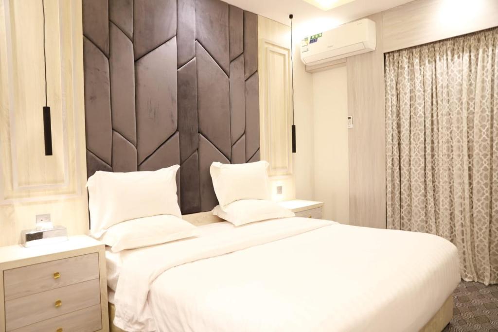 a bedroom with a white bed and a wooden headboard at فندق المساء in Abha