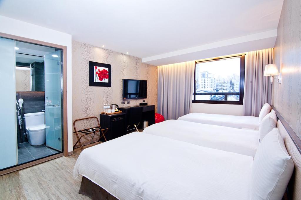 a hotel room with two beds and a bathroom at Talmud Hotel Taichung in Taichung